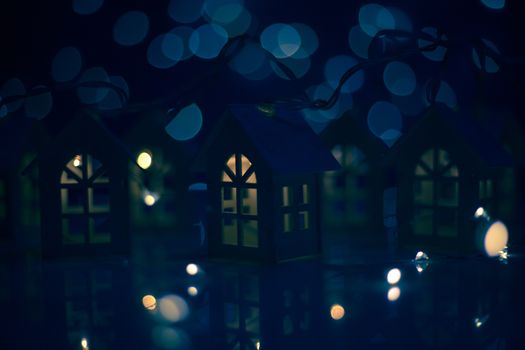 Christmas card of small glowing toy houses garland over bokeh lights background with copy space for text