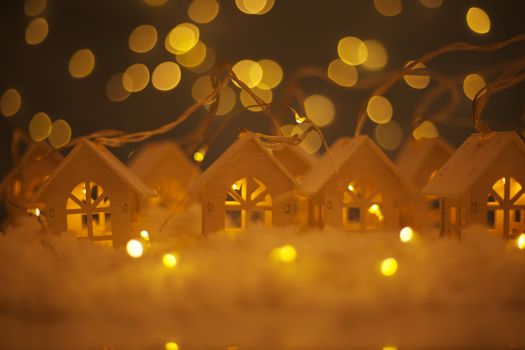 Christmas card of small glowing toy houses garland over bokeh lights background with copy space for text