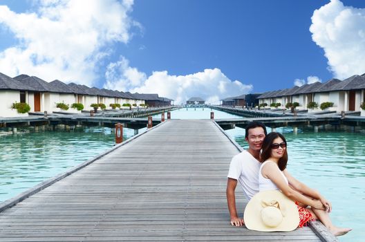 Asian couple on a tropical beach jetty at villa water resort,Maldives