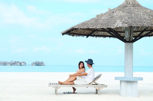 Asian couple on a tropical beach at Maldives.Travel magazine concept.