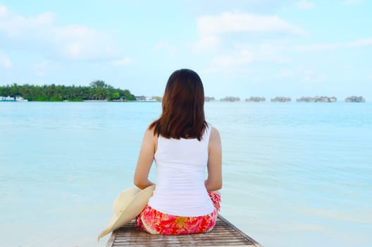 Beautiful asian woman sitting and  relaxed at tropical beach in Maldives