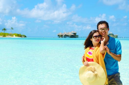 Young happy asian couple  in sunhat on white beach at summer vacation in Maldives island