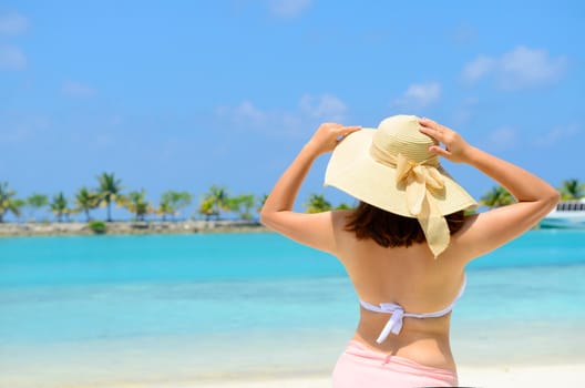 Beautiful asian young woman in sunhat  relaxed at tropical beach in Maldives