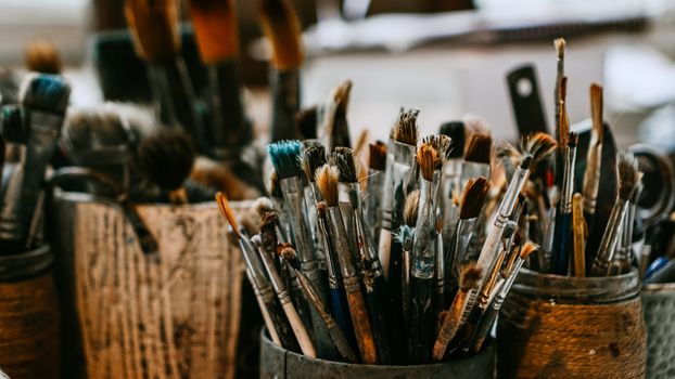 Table with brushes and tools in an art workshop. Background.