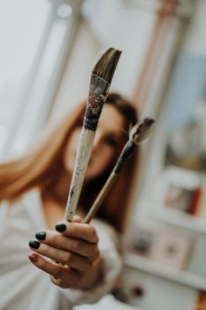 Female artist hand holding paintbrush at art workshop