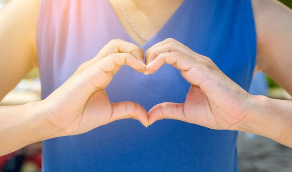 The hands of women and men are the heart shape with the sun light passing through the hands