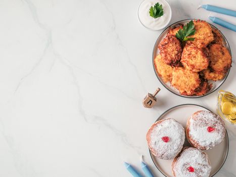 Jewish holiday Hanukkah concept and background. Hanukkah food, oil, candles and traditional spinnig dreidl. Top view or flat lay. Copy space for text.