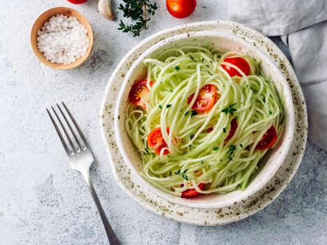 Zucchini noodles salad with cherry tomatoes. Vegetable noodles - green zoodles or courgette spaghetti salad ready-to-eat. Clean eating, raw vegetarian food concept. Copy space. Top view or flat lay.