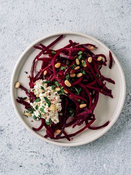 Raw beetroot spaghetti salad with soft cheese,nuts,thyme.Vegetable noodles - Fresh Beetroot Noodles with Ricotta and fresh thyme on plate. Copy space.Clean eating, raw vegetarian food concept.Top view