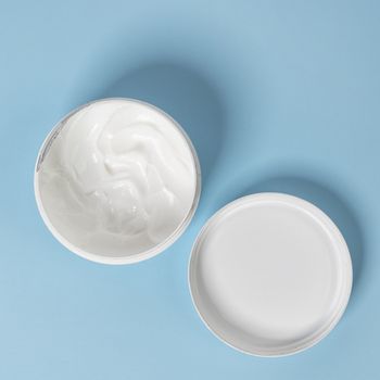 a jar of moisturizer cream on a blue surface