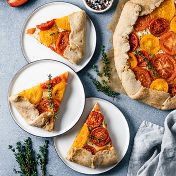 Savory fresh homemade tomato tart or galette.Ideas and recipes for healthy lunch,appetiezer- whole wheat or rye-wheat pie with tomatoes,parmesan cheese,mozzarella.Harvest tomatoes.Top view or flat lay