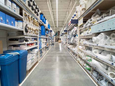 Store for home improvement and DIY. Warehouse aisle of building materials in industiral store. Bit dumpster, pipes. Shallow DOF