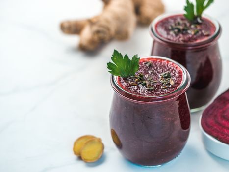 Fresh beetroot and ginger root smoothie. Beetroot smoothie in glass jar on white table. Shallow DOF. Copy space for text. Clean eating and detox concept, recipe idea.