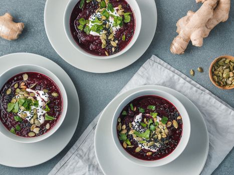 Ideas and recipes for healthy soup - Beetroot and ginger soup puree. Clean eating, detox, vegetarian diet concept. Top view of plate with perfect beet soup, dressed pepitas, sesame and parsley