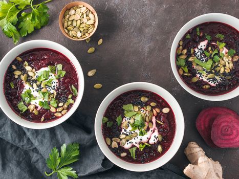 Ideas recipes for healthy soup - Beetroot and ginger soup puree. Clean eating, detox, vegetarian diet concept. Top view of plate with perfect beet soup, dressed pepitas, sesame and parsley. Copy space