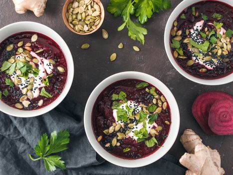 Ideas and recipes for healthy soup - Beetroot and ginger soup puree. Clean eating, detox, vegetarian diet concept. Top view of plate with perfect beet soup, dressed pepitas, sesame and parsley