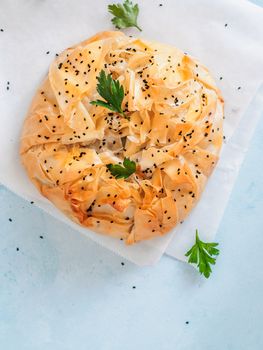 Greek pie spanakopita on blue background. Vegetarian or vegan Spanakopita Spinach Pie from fillo pastry. Copy space. Ideas and recipes for healthy lunch. Top view or flat lay. Vertical.