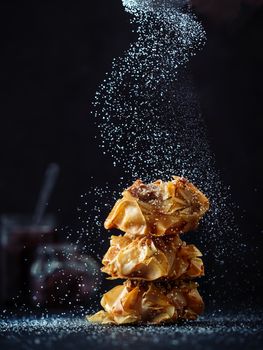 Ideas and recipes for sweet baking. Fillonuts - peanut butter and jelly fillo doughnuts sprinkled powdered sugar. On black background. Copy space for text. Vertical.