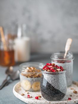 Set of chia pudding in different glass jars on table. Assortment of chia puding with different fruits, nuts,ingredients. Copy space for text. Superfood, detox,healthy overnight breakfast concept