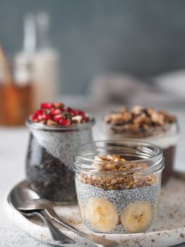 Set of chia pudding in different glass jars on table. Assortment of chia puding with different fruits, nuts,ingredients. Copy space for text. Superfood, detox,healthy overnight breakfast concept