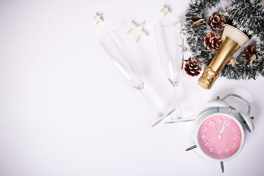 Christmas or New Year composition. Champagne bottle with two glasses, decoration and a clock showing almost midnight, on white background. Christmas, New Year concept. Flat lay,  top view.