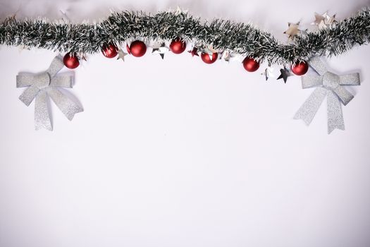 Christmas composition. Garland with red balls, stars and glittery bows on white background. Christmas, winter, new year concept. Flat lay, top view, copy space.