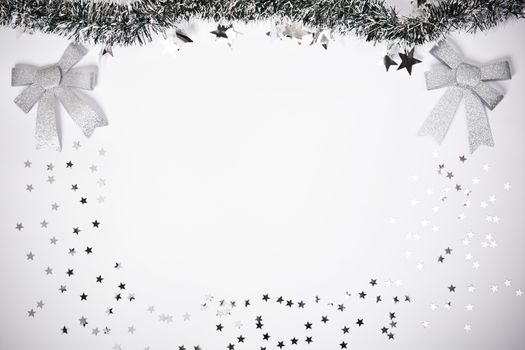 Christmas composition. Garland with silver stars and glittery bows on white background. Christmas, winter, new year concept. Flat lay, top view, copy space.