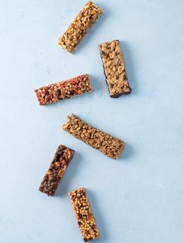 Granola bar on blue background. Set of different granola bars on white marble table. Shallow DOF. Top view or flat lay. Vertical.