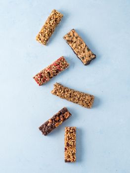 Granola bar on blue background. Set of different granola bars on white marble table. Shallow DOF. Top view or flat lay. Vertical.