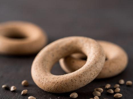 Ring-shaped cracknel with whole grain hemp seed flour and hemp seeds on black background. ring-shaped cracknel close up. Copy space