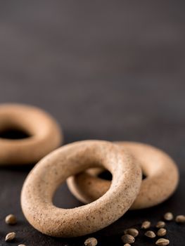 Ring-shaped cracknel with whole grain hemp seed flour and hemp seeds on black background. ring-shaped cracknel close up. Copy space Vertical.