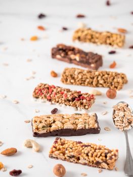 Granola bar with copy space. Set of different granola bars on white marble table. Shallow DOF. Vertical.