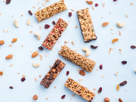 Granola bar on blue background. Set of different granola bars on white marble table. Shallow DOF. Top view or flat lay.