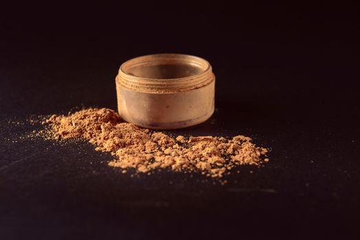 Isolated make-up powder with container on black background.