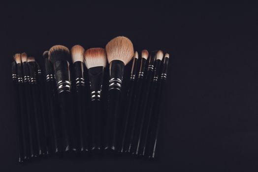 A photograph of Isolated make-up powder with brush on black background