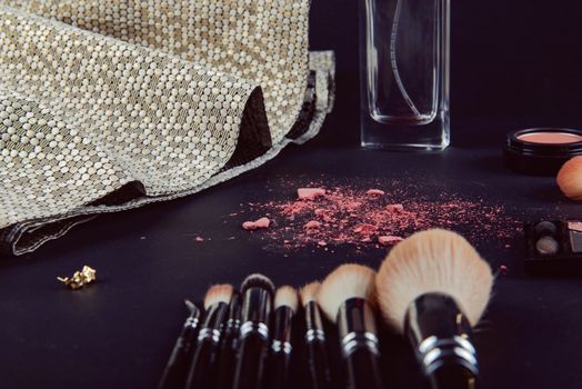 A photograph of Isolated make-up powder with brush on black background