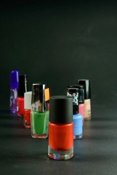 a photograph of coloured nail polish bottles on dark background
