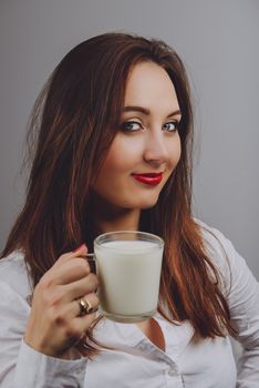 Cheerful girl holding milk mug in hand. Milk is a source of calcium