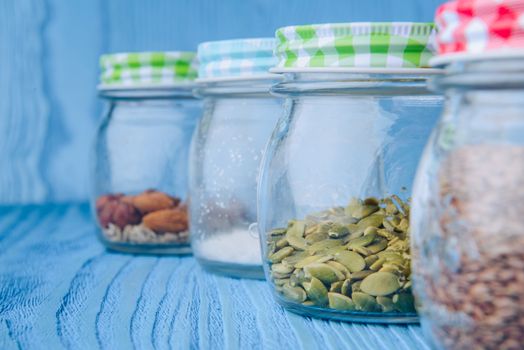 Almonds in a jar on the blue wooden table.