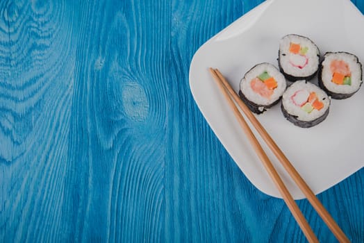 Appetizing tasty Japan rolls on a plate isolated on blue wooden background