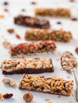 Granola bar with copy space. Set of different granola bars on white marble table. Shallow DOF. Vertical.