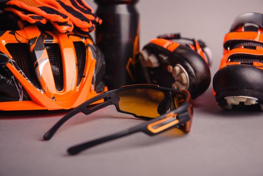 Helmet, gloves, shoes and water bottle - bicycle accessories. Orange color