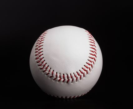 One new white baseball ball with red thread isolated on black background