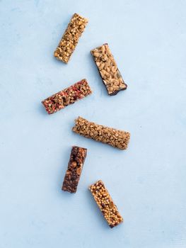 Granola bar on blue background. Set of different granola bars on white marble table. Shallow DOF. Top view or flat lay. Vertical.