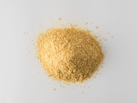 Nutritional yeast heap on white background. Nutritional inactive yeast top view. Copy space. Nutritional yeast is vegetarian superfood with cheese flavor, for healthy diet