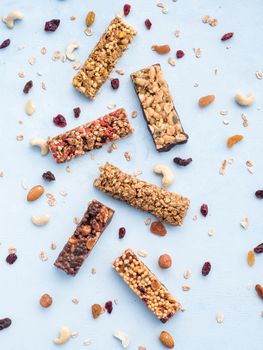 Granola bar on blue background. Set of different granola bars on white marble table. Shallow DOF. Top view or flat lay. Vertical.