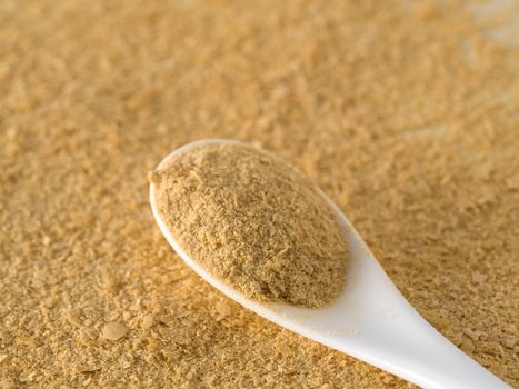 Nutritional yeast background. Nutritional inactive yeast in white spoon. Copy space. Top view. Nutritional yeast is vegetarian superfood with cheese flavor, for healthy diet