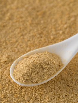 Nutritional yeast background. Nutritional inactive yeast in white spoon. Copy space. Top view. Nutritional yeast is vegetarian superfood with cheese flavor, for healthy diet. Vertical.