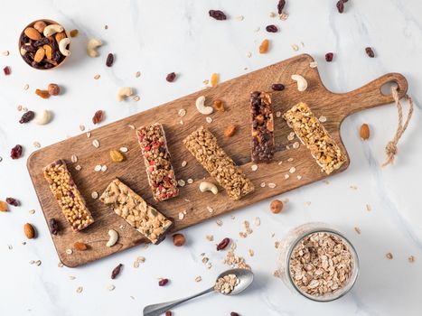 Granola bar with copy space. Set of different granola bars on cutting board over white marble table. Shallow DOF. Top view or flat lay.