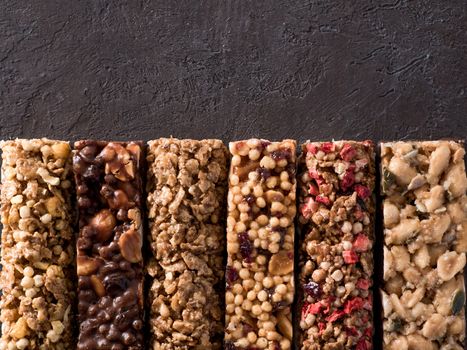 Granola bar with copy space. Set of different granola bars on black background. Shallow DOF. Top view or flat lay.
